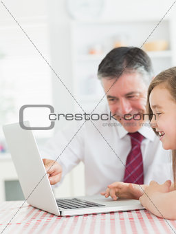 Man sitting with his daughter at the kitchen at laptop