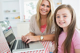 Woman typing at the laptop with daughter