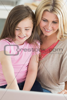 Mum and child sitting and smiling at laptop