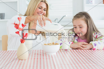 Woman pouring milk into a glass for daughter
