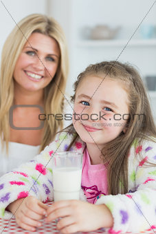 Little girl drinking a glass of milk with her mum