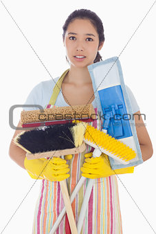 Frowning woman holding brushes and mops