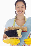 Smiling woman holding cleaning tools
