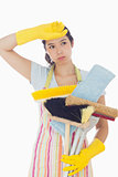 Overworked woman holding cleaning tools