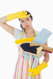 Tired woman holding cleaning tools