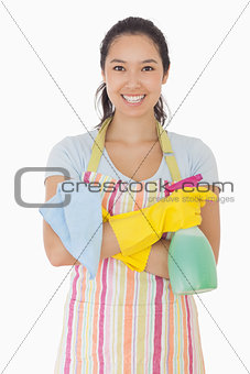 Woman standing with arms crossed holding cleaning products
