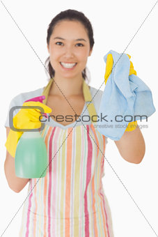 Smiling woman holding up rag and spray bottle
