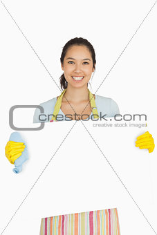 Woman in apron and rubber gloves holding white surface