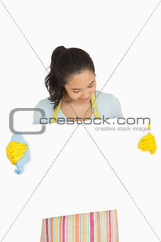 Woman in rubber gloves looking at white surface she is holding
