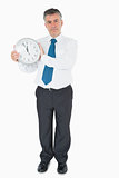 Serious businessman holding clock