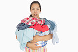 Frowning woman holding basket which is full of dirty laundry