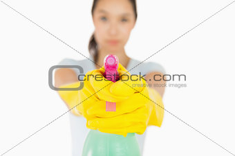 Serious woman pointing a spray bottle at the camera