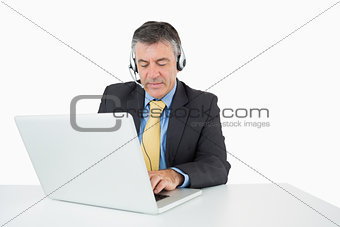 Serious man sitting at his desk with headphones
