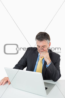 Thoughtful man sitting at his desk with laptop