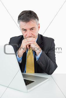 Serious man sitting at his desk with laptop