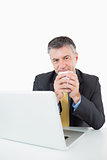 Smiling man drinking coffee at his desk