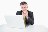 Happy man drinking coffee at his desk