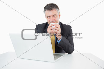 Happy man drinking coffee at his desk