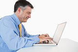 Man smiling while writing on his laptop