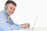 Smiling man with headphones typing on his laptop