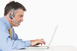 Serious man with headset typing on laptop