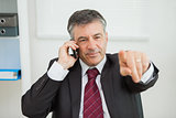 Businessman phoning and pointing