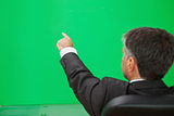 Businessman pointing on a green wall