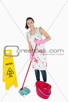 Woman cleaning near a caution sign