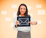 Woman standing smiling while holding a tablet pc and pointing to mail symbol