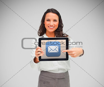 Businesswoman smiling while holding a tablet computer and pointing to mail symbol