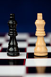 Black and white queen standing at the chessboard against blue background