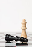 Black chess piece lying while white standing