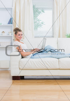 Woman using laptop lying on the couch