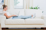 Blond woman looking at the laptop on the couch