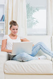 Woman lying on the couch with laptop