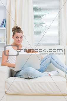 Woman lying on the couch with laptop