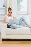 Woman typing on laptop while relaxing
