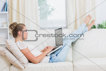 Woman sitting on sofa while using laptop
