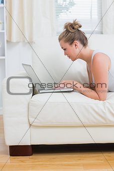 Woman using the notebook while lying on the sofa
