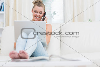 Woman holding a smartphone while using laptop