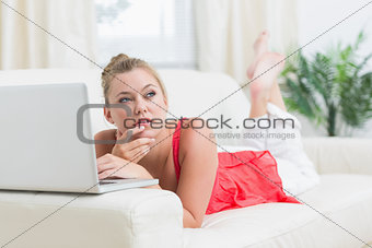 Woman looking thoughtful while using laptop
