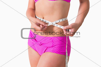 Woman wearing bikini while measuring waist
