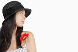 Cheerful woman with flower looking away wearing a hat