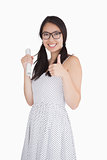 Woman giving thumbs up and holding rolled up piece of paper