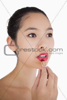 Woman putting on pink lipstick