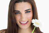 Brunette holding a flower and smiling