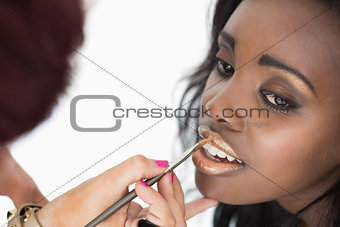 makeup artist applying golden lip gloss