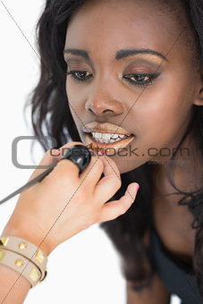 Woman getting golden lip gloss applied