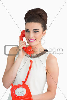 Woman dressed in sixties style holding an old phone