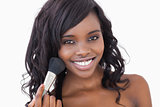 Woman smiling while holding a makeup brush